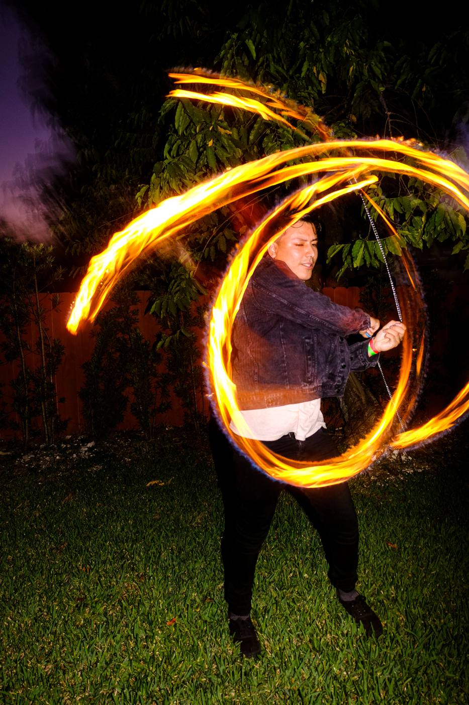 Fire spinner swinging flaming rings on the lawn