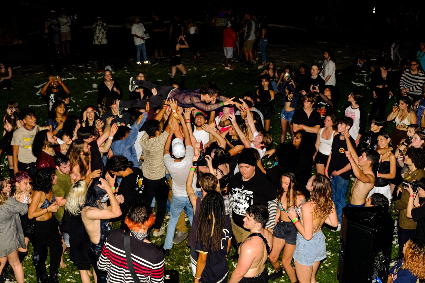 Packed backyard crowd with arms up and a crowd surfer overhead