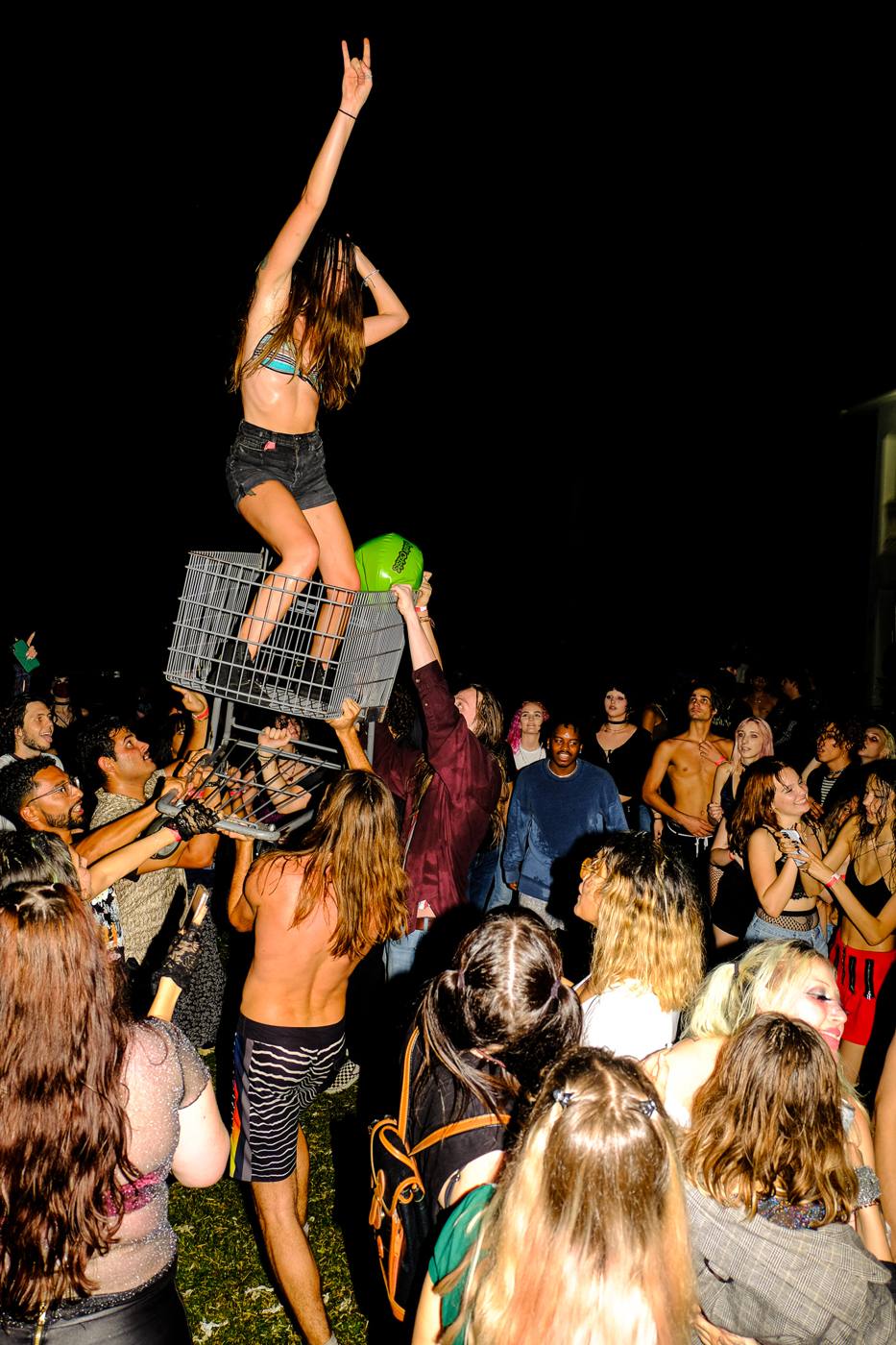 Partygoer standing in a shopping cart held up by the crowd at a past Punk Mansion Party