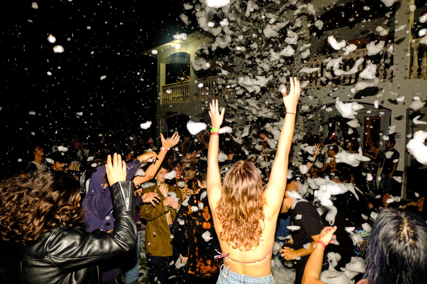 Crowd with hands up under a storm of foam